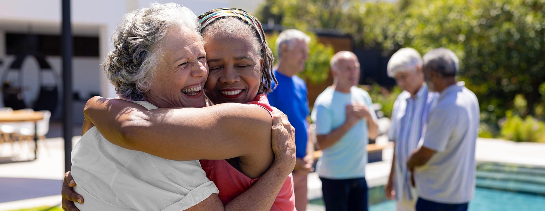 Senior residents smiling and embracing outside.